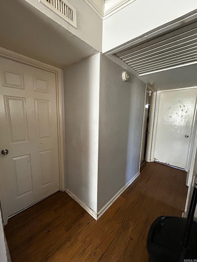 hall with wood finished floors, visible vents, and baseboards