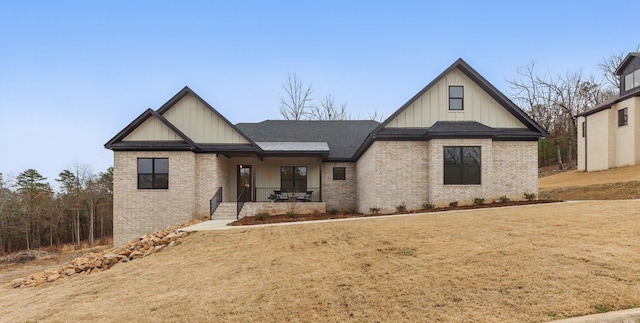 view of front of home featuring a porch, a front yard, brick siding, and board and batten siding