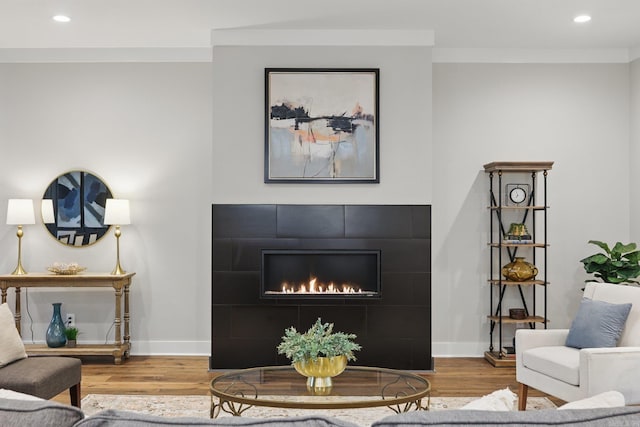 living room with a tile fireplace, recessed lighting, baseboards, and wood finished floors