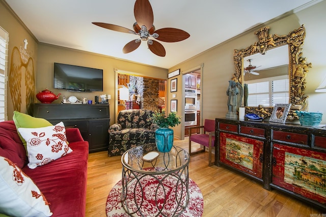 living area featuring a ceiling fan, ornamental molding, and wood finished floors