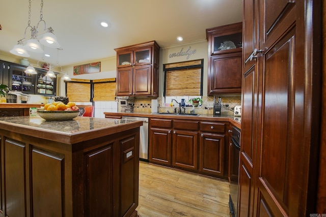 kitchen with light wood-style flooring, a sink, stainless steel dishwasher, decorative backsplash, and a center island