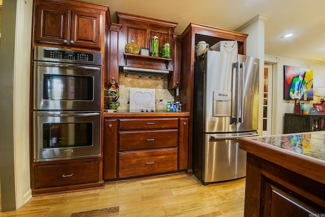 kitchen featuring decorative backsplash, ornamental molding, appliances with stainless steel finishes, light wood-style floors, and recessed lighting