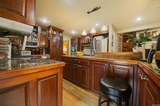 kitchen with stainless steel appliances, a sink, ornamental molding, tile counters, and decorative light fixtures