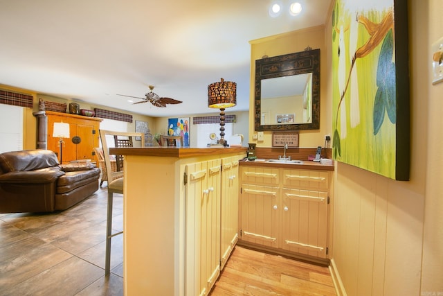 kitchen with ceiling fan, a peninsula, a sink, a kitchen breakfast bar, and open floor plan