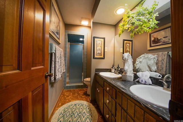 bathroom with a sink, a shower stall, toilet, and double vanity