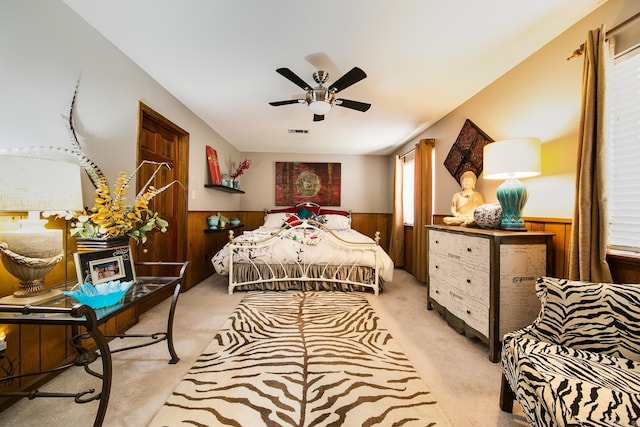 carpeted bedroom with visible vents, wainscoting, ceiling fan, and wooden walls