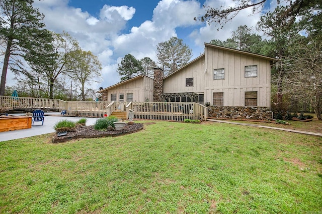 rear view of house featuring board and batten siding, a lawn, and a deck