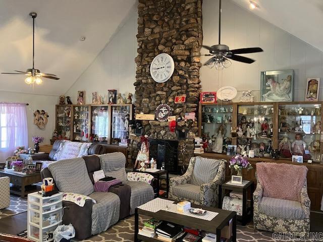 living area with ceiling fan, high vaulted ceiling, and a fireplace