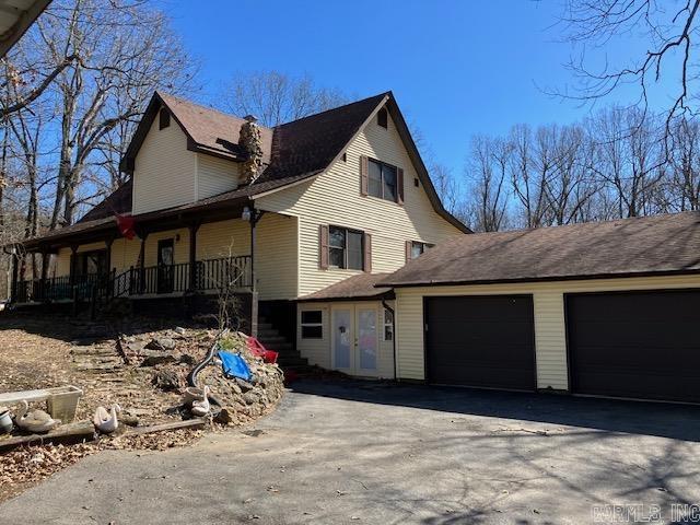 view of side of property with an attached garage, driveway, stairway, and a porch