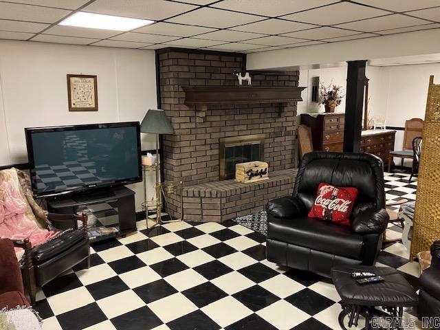 living room with a brick fireplace, a paneled ceiling, and tile patterned floors