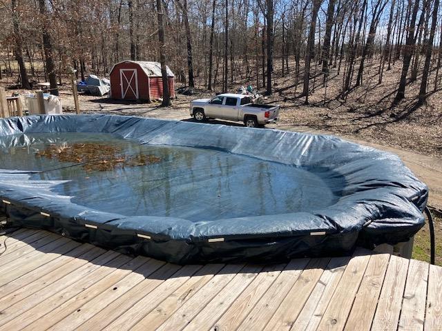 view of pool featuring a shed, an outdoor structure, and a wooden deck