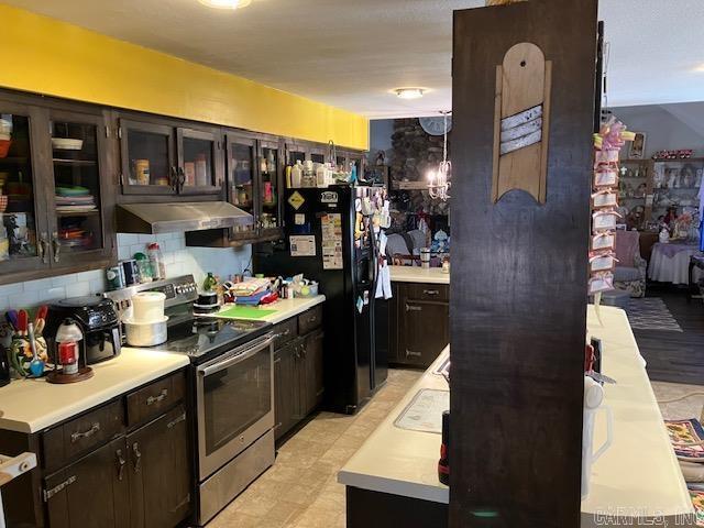 kitchen with tasteful backsplash, freestanding refrigerator, stainless steel electric range, light countertops, and under cabinet range hood