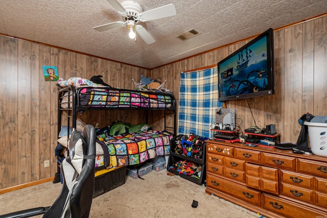 bedroom featuring carpet floors, wood walls, visible vents, baseboards, and a ceiling fan