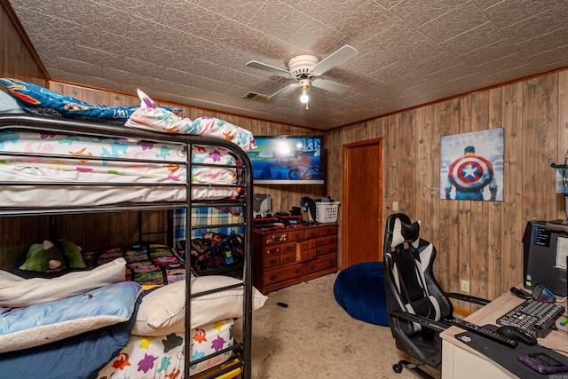 carpeted bedroom with ceiling fan, wooden walls, and visible vents