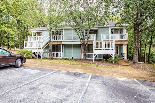 view of front of house with stairs, uncovered parking, and a porch