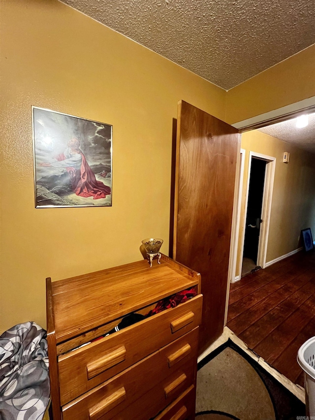 interior space with wood-type flooring, a textured ceiling, and baseboards