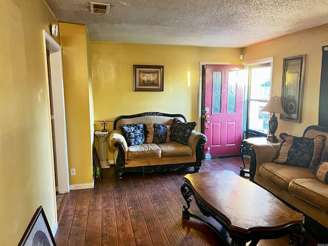 living room with baseboards, visible vents, a textured ceiling, and hardwood / wood-style floors