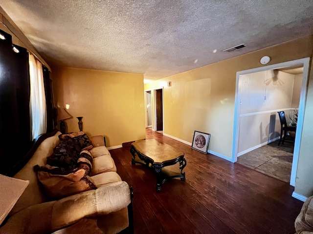 living room with baseboards, a textured ceiling, visible vents, and hardwood / wood-style floors