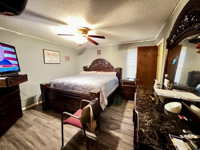 bedroom with ceiling fan, a textured ceiling, baseboards, and wood finished floors