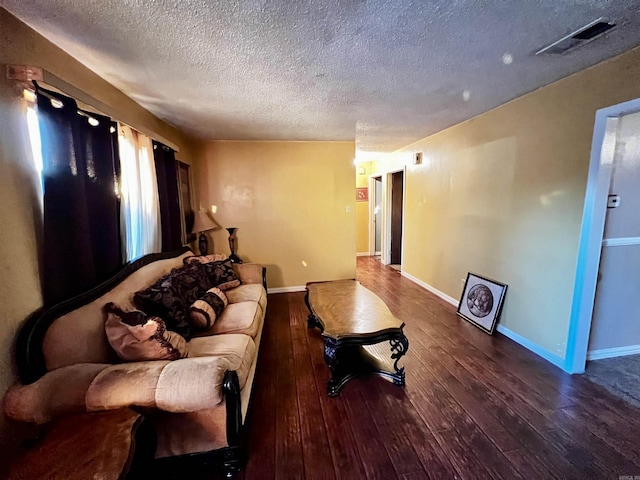 living room featuring a textured ceiling, wood-type flooring, visible vents, and baseboards