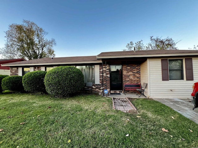 view of front of house with entry steps, a patio area, brick siding, and a front lawn