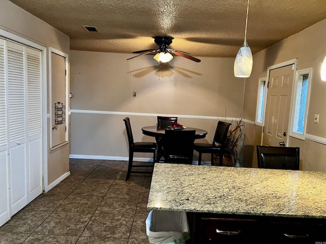 dining area with baseboards, visible vents, a ceiling fan, dark tile patterned flooring, and a textured ceiling