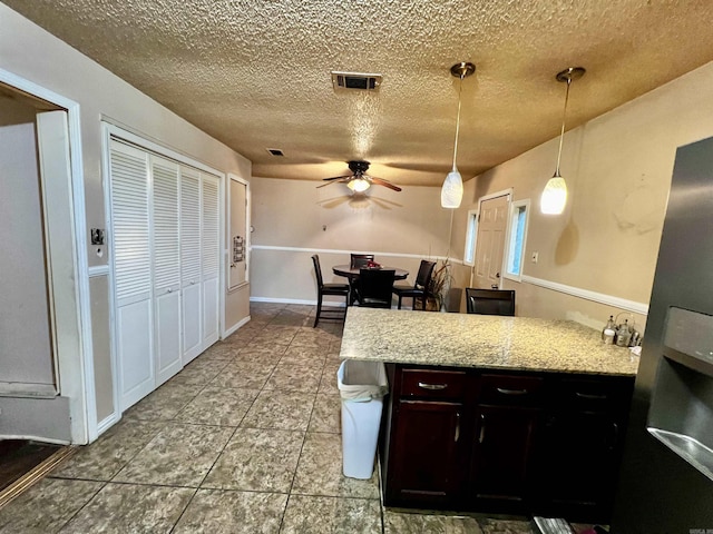 kitchen featuring a peninsula, ceiling fan, a textured ceiling, and hanging light fixtures