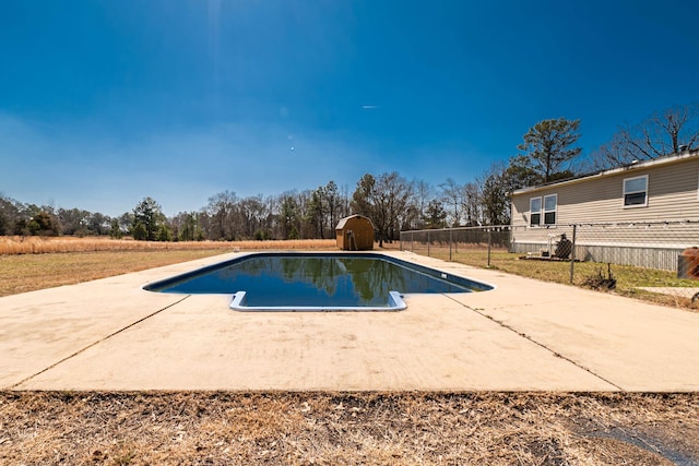 view of pool featuring an outbuilding, a storage shed, fence, a fenced in pool, and a patio area