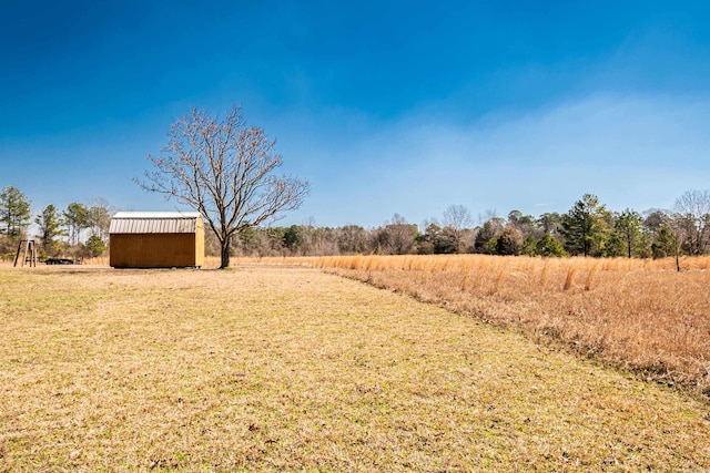 view of yard featuring a shed, a rural view, and an outdoor structure