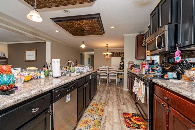 kitchen with light wood finished floors, appliances with stainless steel finishes, pendant lighting, and crown molding