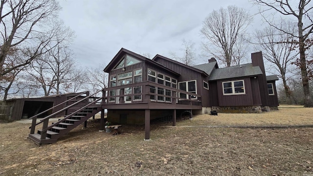 rear view of property with a shingled roof, a deck, a chimney, and stairs