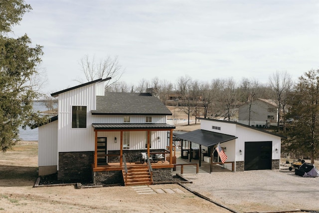 rear view of property with a shingled roof, stone siding, metal roof, a standing seam roof, and an outdoor structure