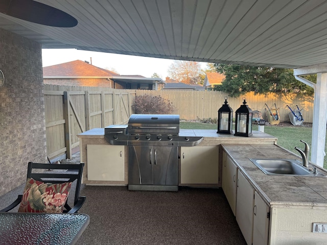 view of patio / terrace with exterior kitchen, a fenced backyard, grilling area, and a sink