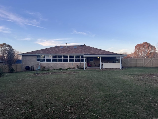 rear view of property with brick siding, a fenced backyard, a patio area, and a yard