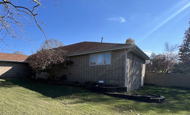 view of side of property featuring crawl space, fence, a lawn, and brick siding