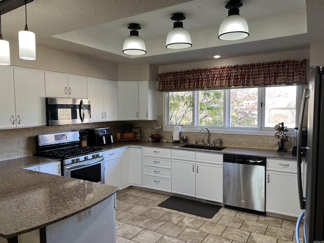 kitchen featuring appliances with stainless steel finishes, a raised ceiling, a sink, and backsplash