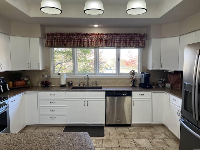 kitchen with stainless steel appliances, white cabinetry, a sink, and backsplash