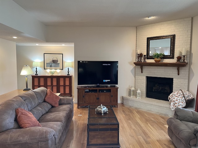 living area featuring light wood-style floors, a brick fireplace, baseboards, and recessed lighting