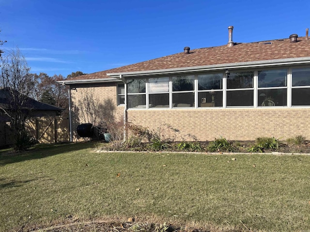 rear view of property featuring a yard, roof with shingles, and stucco siding