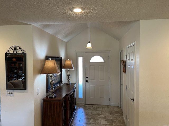 entryway with vaulted ceiling, a textured ceiling, and baseboards