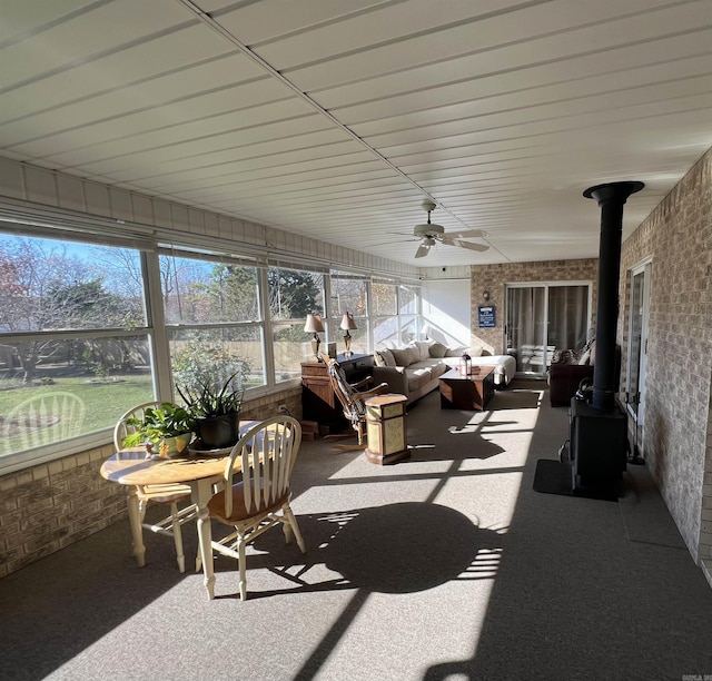 sunroom / solarium with a wood stove and a ceiling fan