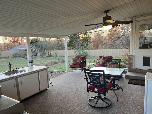 view of patio with outdoor dining space, a fenced backyard, a sink, and a ceiling fan