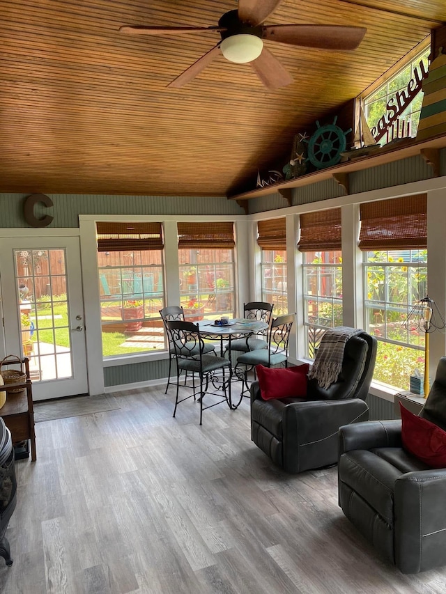 sunroom / solarium with lofted ceiling, wooden ceiling, plenty of natural light, and ceiling fan