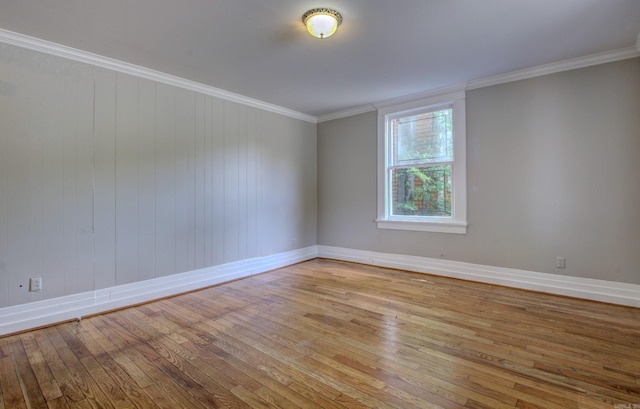 empty room with ornamental molding, wood-type flooring, and baseboards