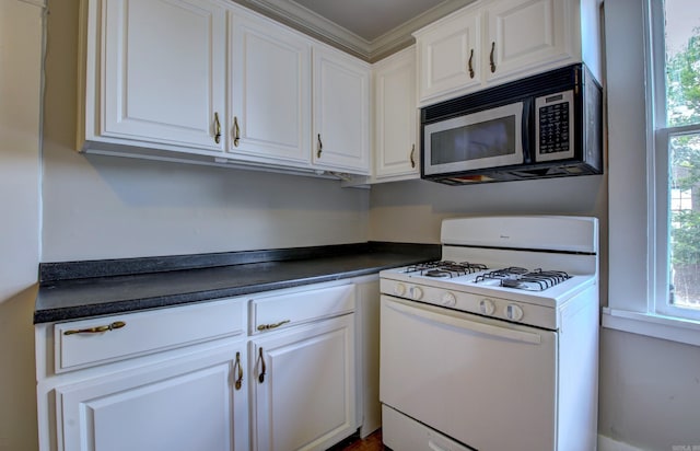 kitchen with dark countertops, white range with gas stovetop, and white cabinets