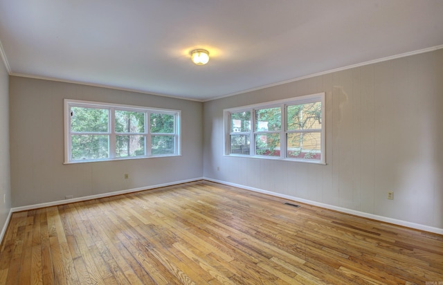 unfurnished room featuring light wood-type flooring, visible vents, crown molding, and baseboards