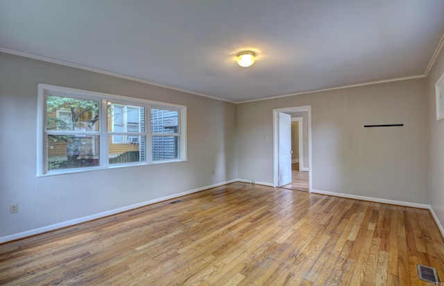 spare room featuring baseboards, light wood-style flooring, visible vents, and crown molding