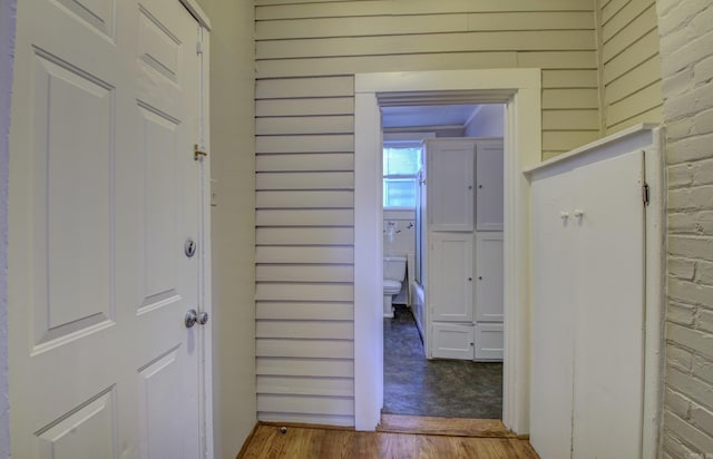 hallway featuring wood finished floors and wooden walls