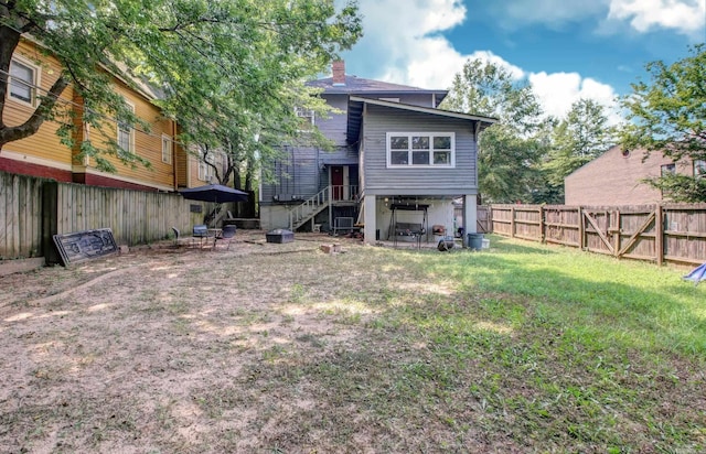 back of house with a fenced backyard, a chimney, and a lawn