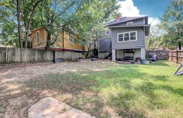 back of house featuring a yard, a chimney, and a fenced backyard